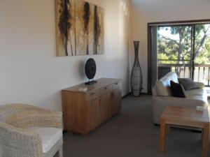 ein Wohnzimmer mit einem Sofa und einem Tisch in der Unterkunft Coolabah Court in Merimbula