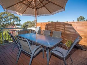 a blue table and chairs on a deck with an umbrella at Fishermans Lodge in Merimbula