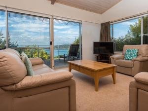 a living room with a couch and a tv and a table at Seascape in Pambula Beach