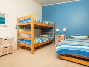 a bedroom with two bunk beds and a blue wall at Seascape in Pambula Beach