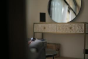 a mirror in a room with a chair and a table at La Demoiselle de Bohardy in Montrevault