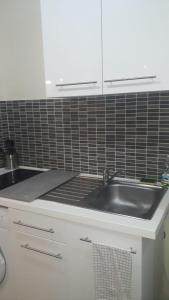 a kitchen with a sink and a black tiled wall at Appartement Mimosa, tram 2, parking in Montpellier