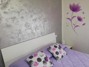 a bedroom with a bed with purple sheets and a flower on the wall at La Casa di Mà in Piancastagnaio