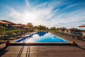 a large swimming pool with lounge chairs and the sun at Schuchmann Wines Château,Villas & SPA in Telavi