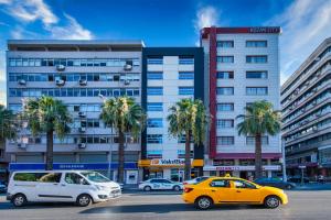 
a yellow car driving down a street next to tall buildings at Kozan City Hotel in İzmir
