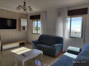 ein Wohnzimmer mit einem blauen Sofa und einem Tisch in der Unterkunft A Casiña do Miramar in A Lanzada
