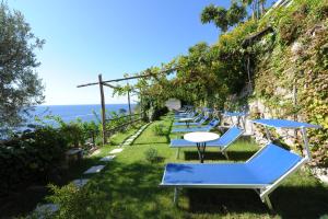 uma fila de cadeiras azuis e mesas na relva em Hotel Torre Saracena em Praiano