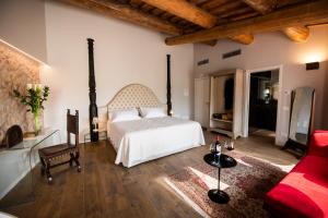 a bedroom with a white bed and a red couch at Magari Estates Boutique Hotel in Colognola ai Colli