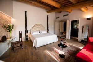 1 dormitorio con cama blanca y sofá rojo en Magari Estates Boutique Hotel, en Colognola ai Colli