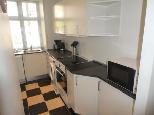 a kitchen with white cabinets and a black counter top at Lillegrund in Copenhagen