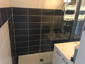 baño con pared de azulejos negros y lavabo en Marinas et mer 25, en Saint-Cyprien