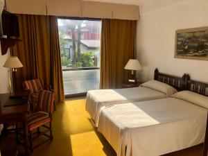 Una habitación de hotel con dos camas y una ventana. en El Ancla, en Laredo