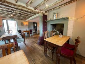uma sala de jantar com uma mesa e uma lareira em The Windmill Inn em Horsham