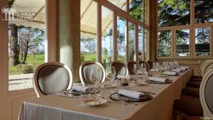 a long table with glasses and napkins in a room with windows at Relais Villa Pomela in Novi Ligure