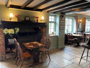 uma sala de jantar com lareira, mesa e cadeiras em The Windmill Inn em Horsham