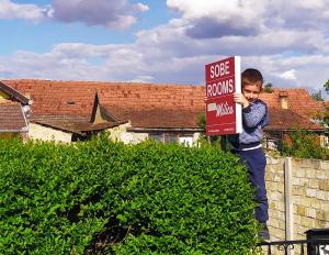 Um rapaz a segurar um cartaz numa sebe. em Soba Milica em Palić
