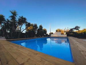 a large blue swimming pool with a wooden deck at La Maison One B&B in Carovigno