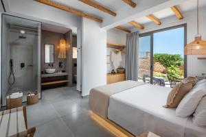 a bedroom with a large white bed and a bathroom at Celestial Lindos Suites in Líndos