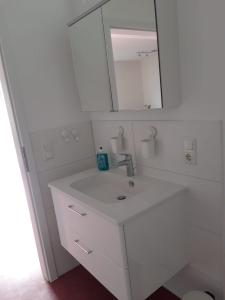 La salle de bains blanche est pourvue d'un lavabo et d'un miroir. dans l'établissement Ferienwohnung Bad Laasphe, à Bad Laasphe