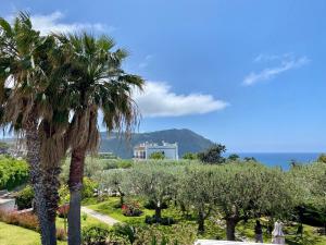 a view of a garden with palm trees and the ocean at Casa delle Sirene in Ischia