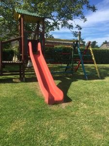 a playground with a red slide in the grass at Domki letniskowe Zacisze in Rusinowo