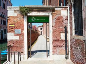 une porte menant à un bâtiment en briques avec un panneau sur celui-ci dans l'établissement Ostello S. Fosca - CPU Venice Hostels, à Venise