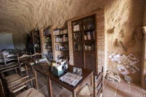 a room with a table and bookshelves at Hábitat Troglodita Almagruz in Purullena