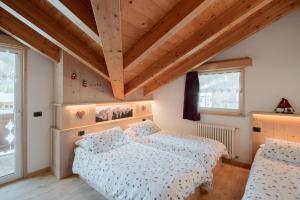 a bedroom with two beds and two windows at Cèsa Castlunger in Canazei