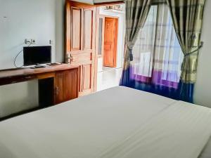 a bedroom with a bed and a tv and a window at RedDoorz Syariah near Sunrise Park Pangandaran in Pangandaran