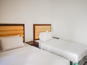 two beds sitting next to each other in a room at RedDoorz Syariah near Sunrise Park Pangandaran in Pangandaran