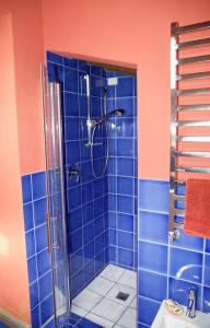 y baño de azulejos azules con ducha y lavamanos. en Colonica Il Picchio Verde, en Altopascio