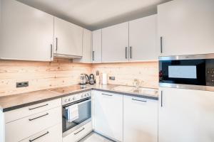 a white kitchen with white cabinets and a microwave at Apart Gstrein - Ski-In & Ski-Out in See