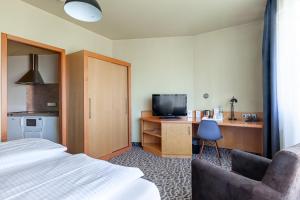 Habitación de hotel con cama y escritorio con TV. en DOBLERGREEN Hotel Stuttgart-Gerlingen, en Gerlingen