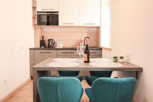 eine Küche mit einem Tisch mit Stühlen und einer Flasche Wein in der Unterkunft Apartament City Center Silver - bezpłatny parking in Krynica-Zdrój