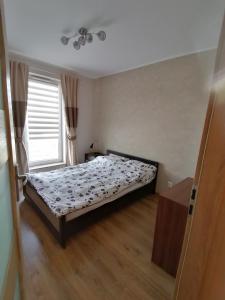 - une chambre avec un lit dans une pièce dotée d'une fenêtre dans l'établissement Apartament SunSet, à Gdynia