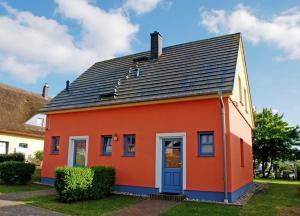 uma casa vermelha com um telhado preto em Ferienappartements Ostsee_ Nixen_ em Lobbe