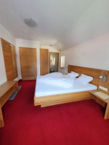 1 dormitorio con 1 cama blanca grande y alfombra roja en Pension Gabl, en Pfunds