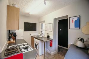 a small kitchen with a stove and a sink at Quirky bohemian Lake District miners cottage- 6 bd in Millom