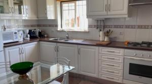 Una cocina con gabinetes blancos y una mesa de vidrio. en Praia da Falésia Alfa Mar Albufeira, en Olhos de Água