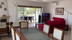 Una sala de estar con una mesa y un sofá rojo. en Praia da Falésia Alfa Mar Albufeira, en Olhos de Água