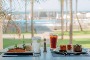 stół z dwoma talerzami jedzenia i drinka w obiekcie Palma Hotel w mieście Port Said