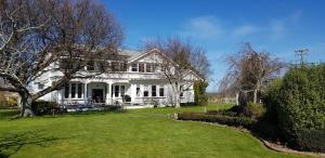 una casa blanca con un gran patio delante en Estancia farm stay en Masterton