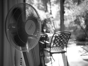 une photo en noir et blanc d'un ventilateur à côté d'un banc dans l'établissement Les Pins, Provence Country Club, à Saumane-de-Vaucluse