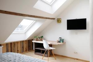 een slaapkamer met een bureau en een tv op zolder bij Cochlea in Marche-en-Famenne