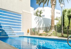 a swimming pool with a palm tree and a building at Parador de Mérida in Mérida