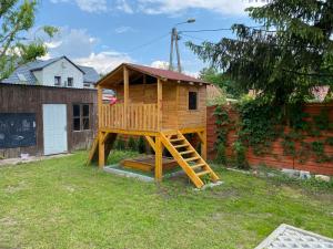 una casa en un árbol con una escalera en un patio en Dom w Santocznie, en Santoczno