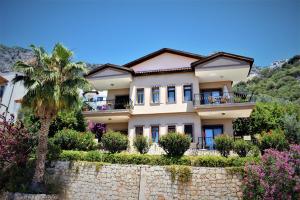 a house with a palm tree and a stone wall at Manzara Apartment in Kas