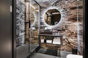 een badkamer met een douche, een wastafel en een spiegel bij Le Petit Marin Boutique Hotel in Rotterdam
