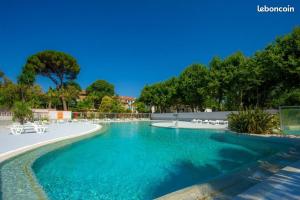 una piscina con acqua blu e sedie bianche di MOBIL HOME Climatisé 6 Personnes au Camping Marvilla Parks - Le Parc Des Septs Fonts ad Agde