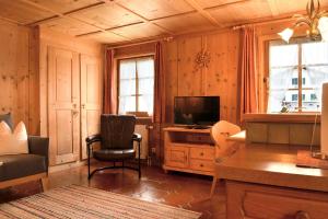 a living room with a television and a chair at Landhaus Huber in Elbigenalp